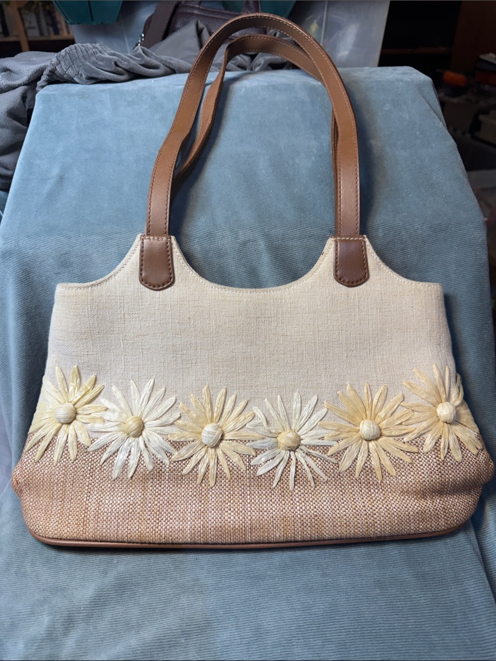 tan CL America handbag features a row of dimensional straw daisy appliqués